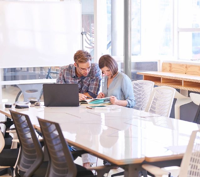 Two people are sitting at a table looking at papers.