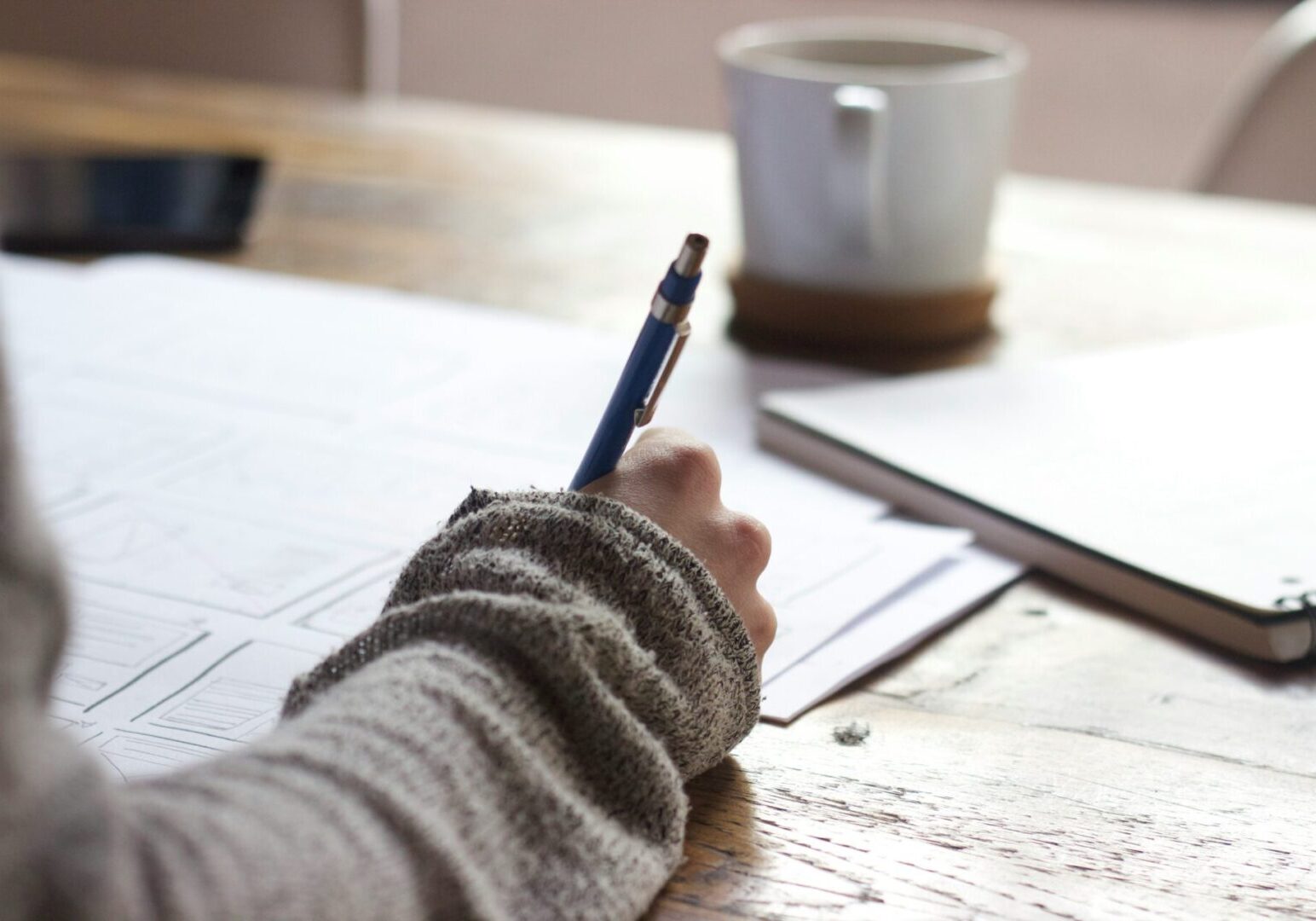 A person writing on paper with a pencil